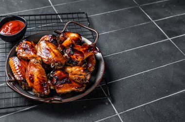 BBQ chicken wings in dip Barbecue sauce. Black background. Top view. Copy space.