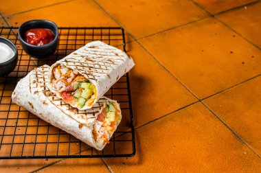 Shawarma durum doner kebab with meat and vegetable salad. Orange background. Top view. Copy space.
