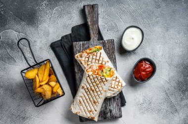 Traditional Mexican roll burritos with meat, vegetable salad and french fries. White background. Top view.