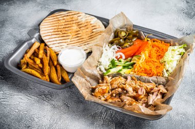 Doner kebab Shawarma on a plate with french fries and salad in box to go, take away. White background. Top view.