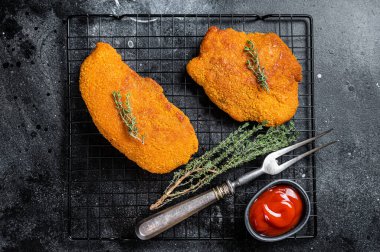 Fried Breaded weiner schnitzel, cooked meat steak. Black background. Top view.