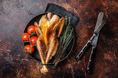 Roast guinea fowl with herbs and spices, cooked game bird. Dark background. Top view.
