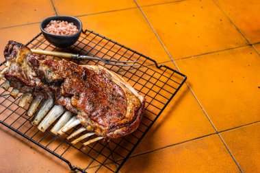 Roast Rack of lamb ribs, spareribs on grill. Orange background. Top view. Copy space.