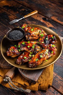 Teriyaki chicken wings with black sesame in a plate. Wooden background. Top view.