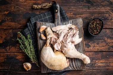 Boiled chicken leg thigh on a wooden board with herbs. Wooden background. Top view.