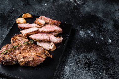 Grilled sliced pork loin steak on marble board. Black background. Top view. Copy space.