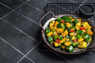 Chinese smashed cucumber salad with chili peppers and sesame seeds. Black background. Top view. Copy space.