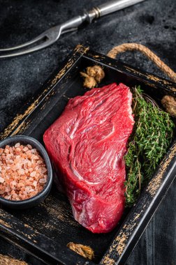 Fresh Raw veal meat with herbs and salt. Black background. Top view.
