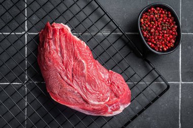Raw beef meat piece for grilling with spices. Black background. Top view.