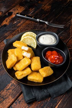 Fried Fish Sticks Fingers with sauce in a plate. Wooden background. Top view.