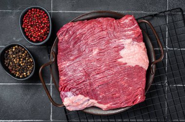 Raw piece of marble beef brisket meat with spices. Black background. Top view.