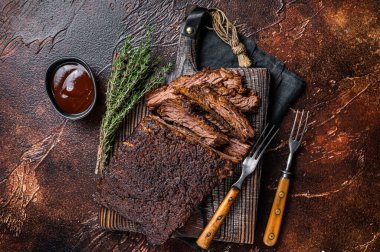 Traditional smoked barbecue wagyu beef brisket on wooden board. Dark background. Top view.