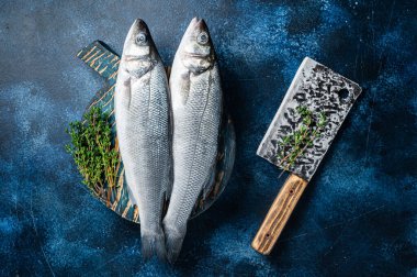 Uncooked Raw Sea Bass fish, Seabass with thyme. Blue background. Top view.