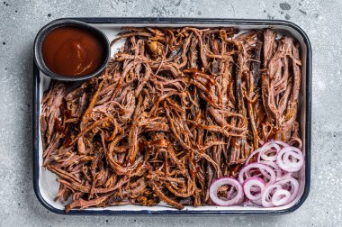 Pulled beef meat with hot chili sauce in baking dish. Gray background. Top view.