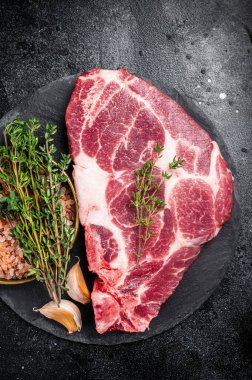 Pork loin steak, raw neck meat with thyme and salt. Black background. Top view.