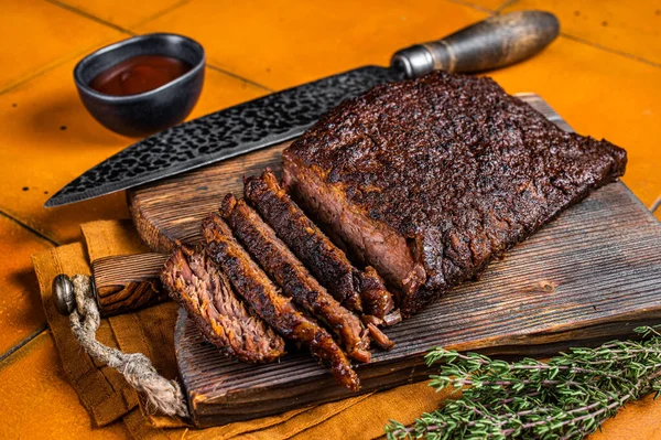 stock image Smoked Barbecue Beef Brisket with Sauce on wooden board. Orange background. Top view.