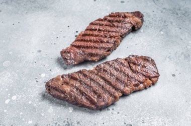 BBQ Grilled denver beef meat steak on a table. Gray background. Top view.