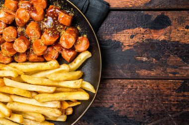 German currywurst meal, curry wurst with french fry served in a plate. Wooden background. Top view.