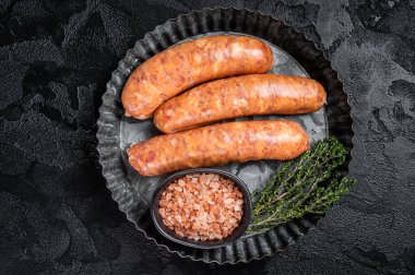 Raw Chorizo sausages ready for cooking with thyme. Black background. Top view.