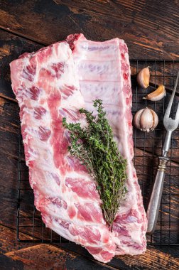 Raw pork spare ribs on a rack with herbs. Wooden background. Top view.