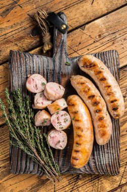 Ahşap servis tahtasının üzerinde ızgara domuz eti sosisi. Ahşap arka plan. Üst Manzara. Boşluğu kopyala.