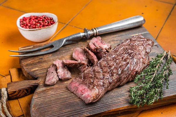 在木制切菜板上烤中罕见的大砍刀或裙子牛肉牛排 橙色背景 顶部视图 — 图库照片