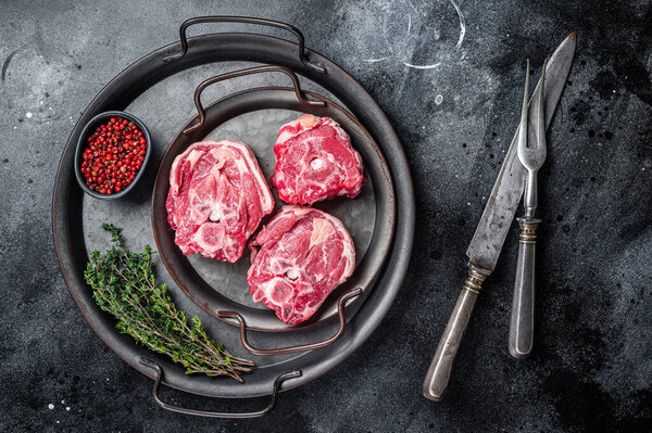 Raw lamb neck meat with bone on a steel tray. Black background. Top view.