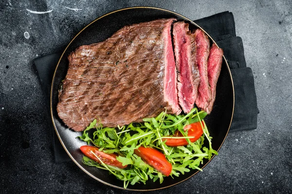 烤中罕见的侧翼牛排和沙拉在盘子里 黑色背景 顶部视图 — 图库照片