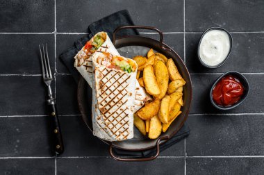 Shawarma Shaurma kebab with meat, vegetable salad and french fries. Black background. Top view.