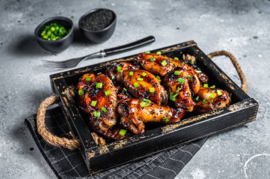 BBQ Chicken wings in Teriyaki sauce with black sesame in a tray. Gray background. Top view.