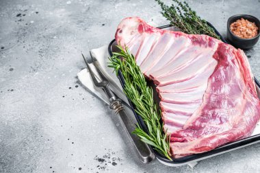 Ready for cooking Rack of lamb, raw mutton ribs with herbs. Gray background. Top view. Copy space.