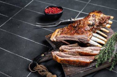 Grilled Rack of lamb ribs, mutton spareribs on wooden board. Black background. Top view. Copy space.