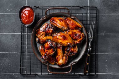 BBQ chicken wings in dip Barbecue sauce. Black background. Top view.