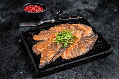 Salmon carpaccio with microgreens on marble board. Black background. Top view.