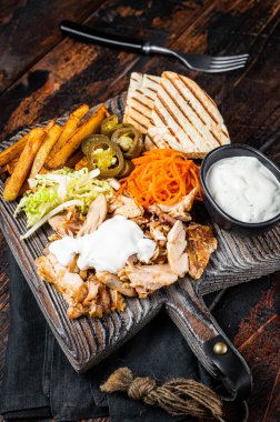 Kebab, Shawarma, Gyro grilled meat with french fries and vegetables on a wooden board. Wooden background. Top view.