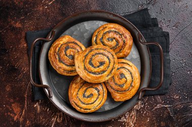 Sweet twisted Bun with poppy seeds and lavender. Dark background. Top view.