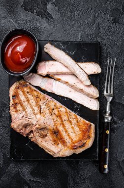 Grilled slised pork Chop or T-bone meat steak. Black background. Top view.