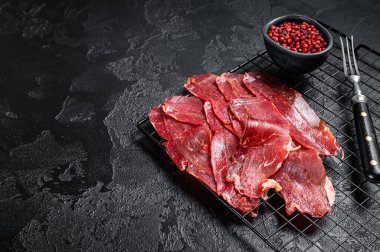 Dried sliced basturma, cured beef meat ready for eat. Black background. Top view. Copy space.