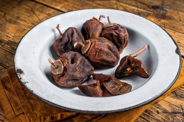 Natural Sun Dried persimmon fruit on a plate. Wooden background. Top view.