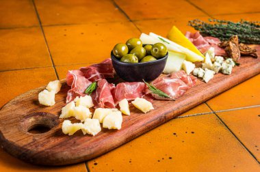 Italian appetizer platter, antipasti snack with Prosciutto ham, Parmesan, Blue cheese, Melon and Olives on wooden board. White background. Top view.