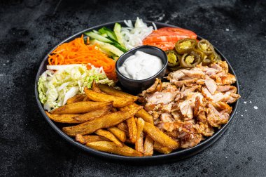 Shawarma Doner kebab on a plate with french fries and salad. Black background. Top view.