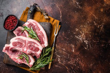 Raw fresh saddle of lamb mutton with herbs and spices on butcher board. Dark background. Top view. Copy space.
