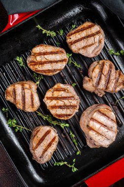 Izgara tavada fileto etinden kızarmış domuz eti bifteği. Karanlık arka plan. Üst görünüm.