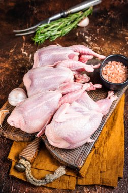 Plucked raw quails, fresh poultry on wooden board with spices. Dark background. Top view. clipart