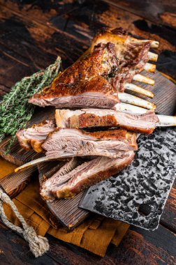 Roast lamb ribs, mutton spareribs, sliced meat on wooden board. Wooden background. Top view.