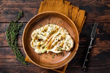 Grilled Cauliflower steaks with a cilantro lime chimichurri sauce, Plant based meat substitute concept. Wooden background. Top view.