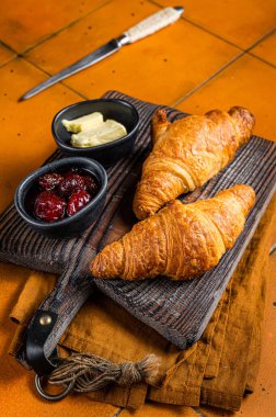 Delicious breakfast with fresh croissants served with butter and jam. Orange background. Top view.