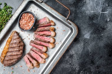 Izgara ve dilimlenmiş Brezilya usulü Picanha bifteği, çelik servis tepsisinde biftek. Siyah arka plan. Üst Manzara. Boşluğu kopyala.