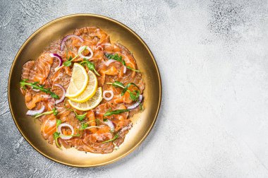 Soğan ve roka ile servis edilmiş taze çiğ somon carpaccio dilimleri. Beyaz arka plan. Üst Manzara. Boşluğu kopyala.