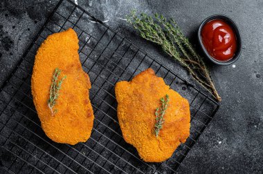 Fried Breaded weiner schnitzel, cooked meat steak. Black background. Top view.